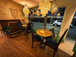 Un interior acogedor con muebles de madera, un ventanal grande y un cartel que dice 'Café & Bar'.
