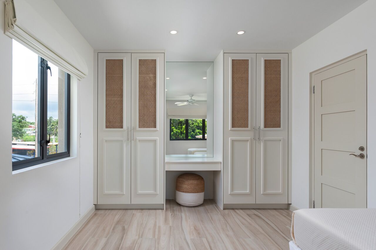 A bedroom with a bed, a window, a ceiling fan, and a wardrobe with a mirror.