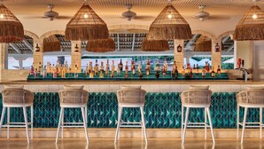 A bar area with a long counter, wicker chairs, and a variety of bottles. - Steps to Beach, Pool, Free Beach Club Access, Ocean/Sunset Views & Spacious! (Lower Carlton)
