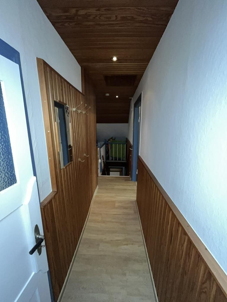 Un estrecho pasillo con paneles de madera en las paredes y suelo alfombrado.
