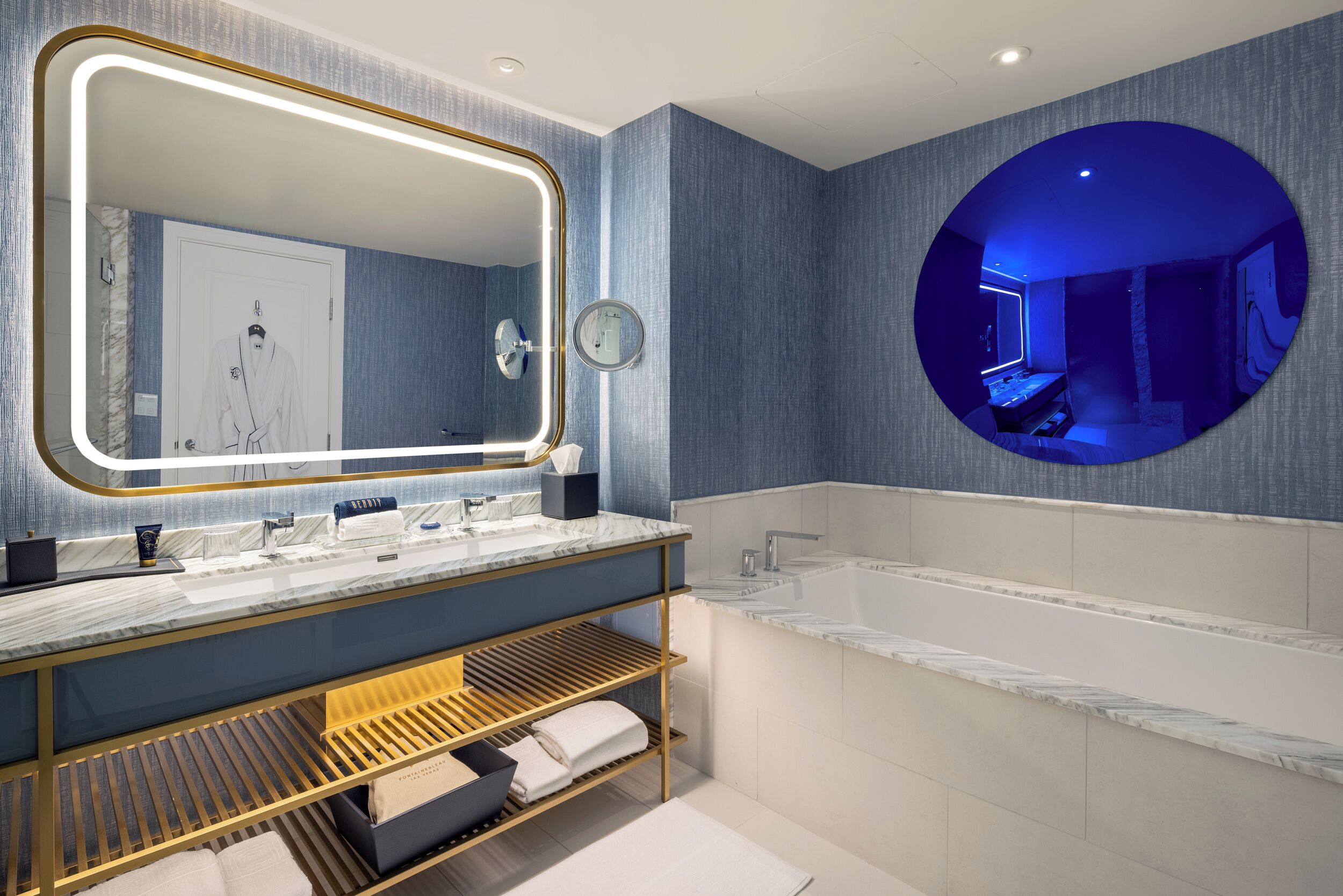 A modern bathroom with a large mirror, dual sinks, and a bathtub.