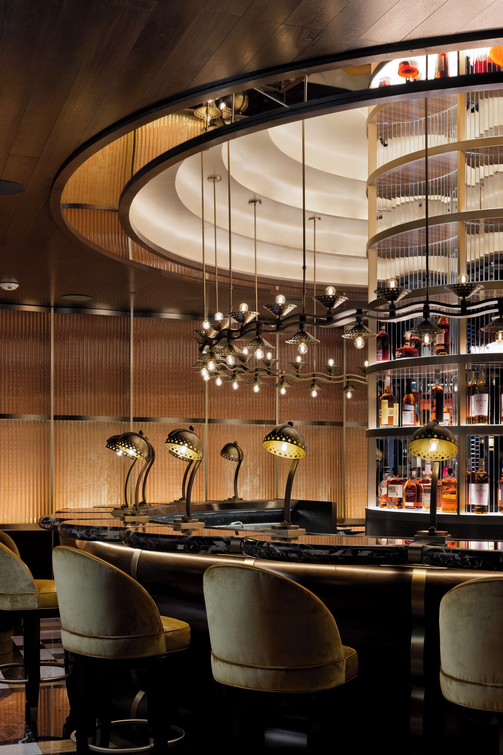 A bar area with a curved ceiling, hanging pendant lights, and a liquor display.