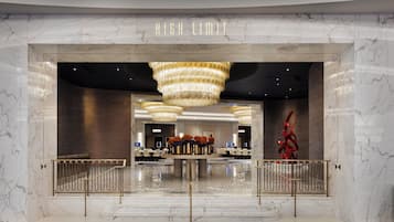 Un hall d’hôtel aux murs de marbre, avec un comptoir d’accueil central et un lustre.