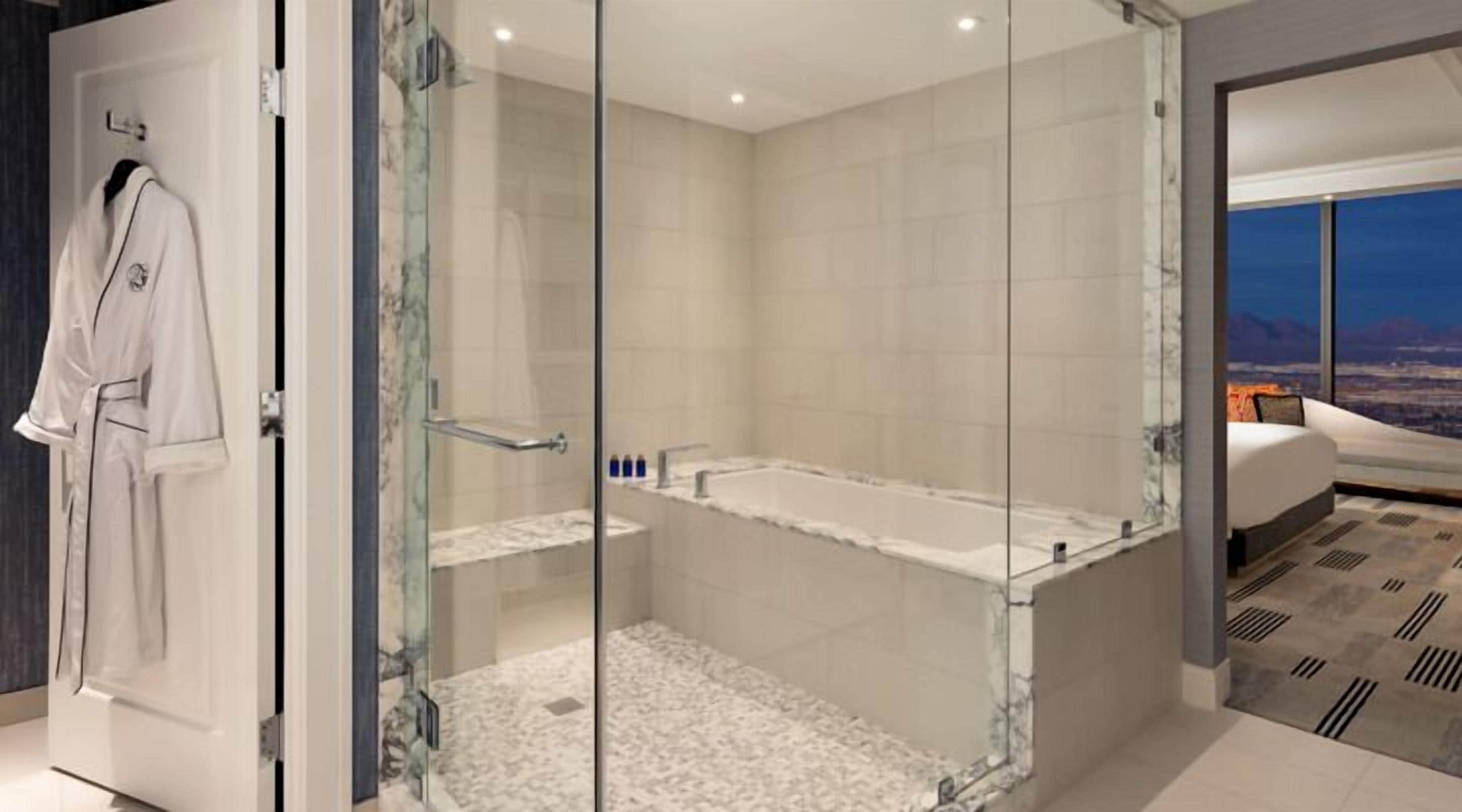 A modern bathroom with a glass-enclosed shower, a bathtub, and a large window offering a city view.