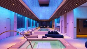 A modern spa area with a large hot tub, seating, and a ceiling with a unique light pattern. - Fontainebleau Las Vegas, MICHELIN Key Award Hotel (Las Vegas)
