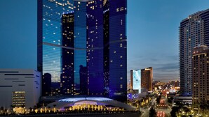 A modern hotel with a distinctive curved facade, multiple floors, and illuminated windows. - Fontainebleau Las Vegas, MICHELIN Key Award Hotel (Las Vegas)