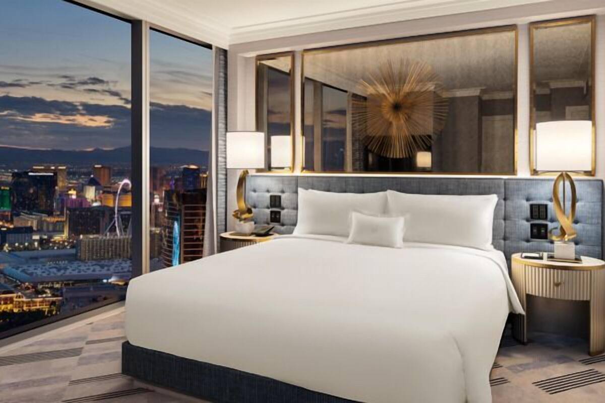 Une chambre d’hôtel moderne avec un grand lit, deux tables de chevet, une vue sur la ville et un miroir décoratif.