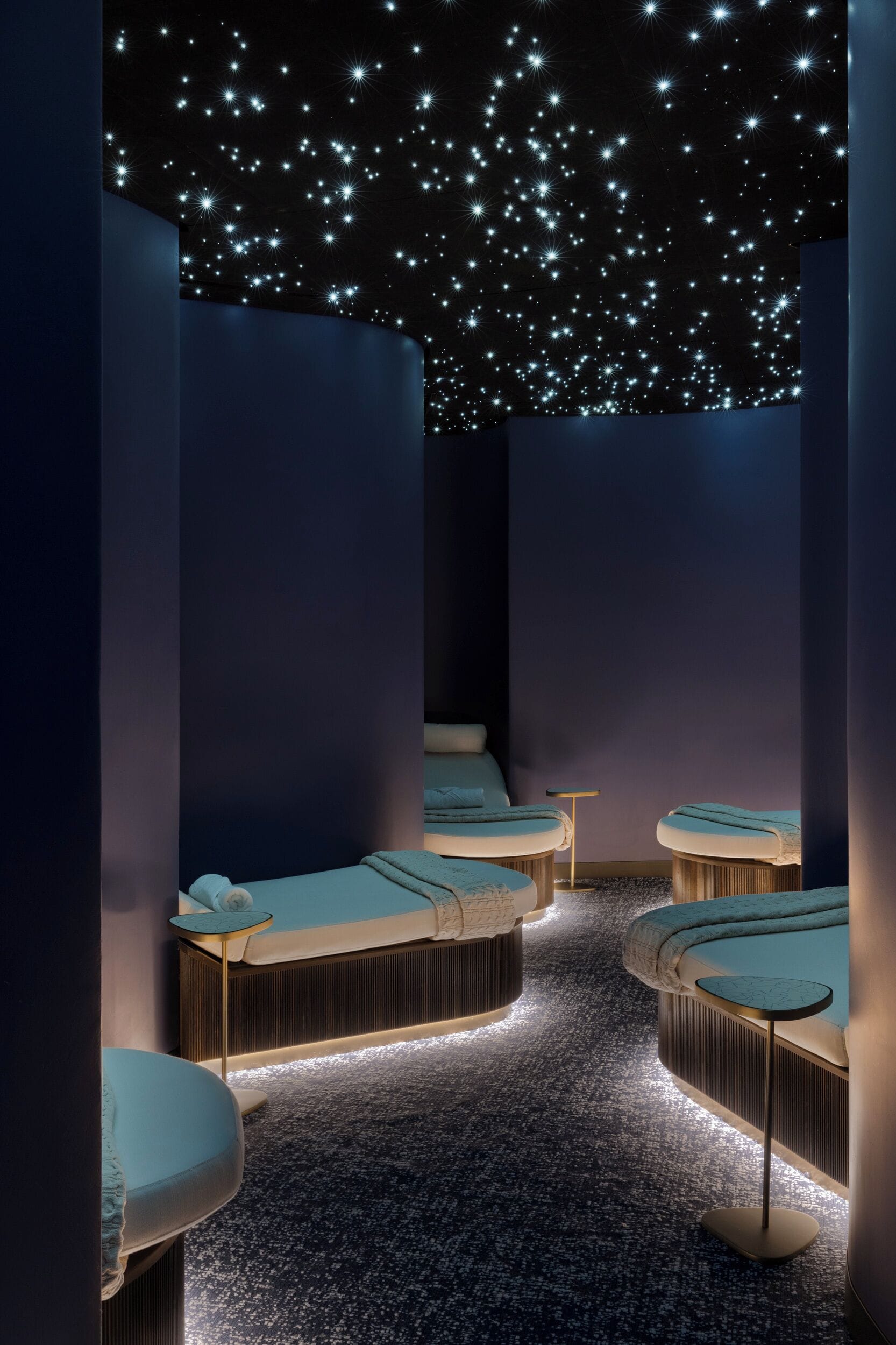 A spa room with starry ceiling, multiple massage tables, and a speckled floor.
