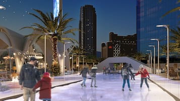 Une patinoire en plein air, avec des palmiers et des bâtiments modernes en arrière-plan.