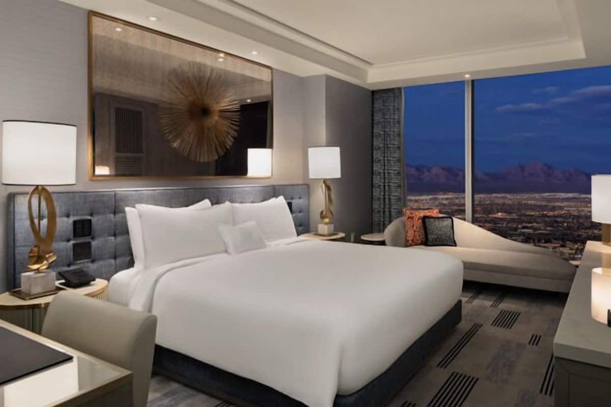 Une chambre d’hôtel moderne dotée d’un grand lit, d’un coin salon et d’une vue sur la ville.