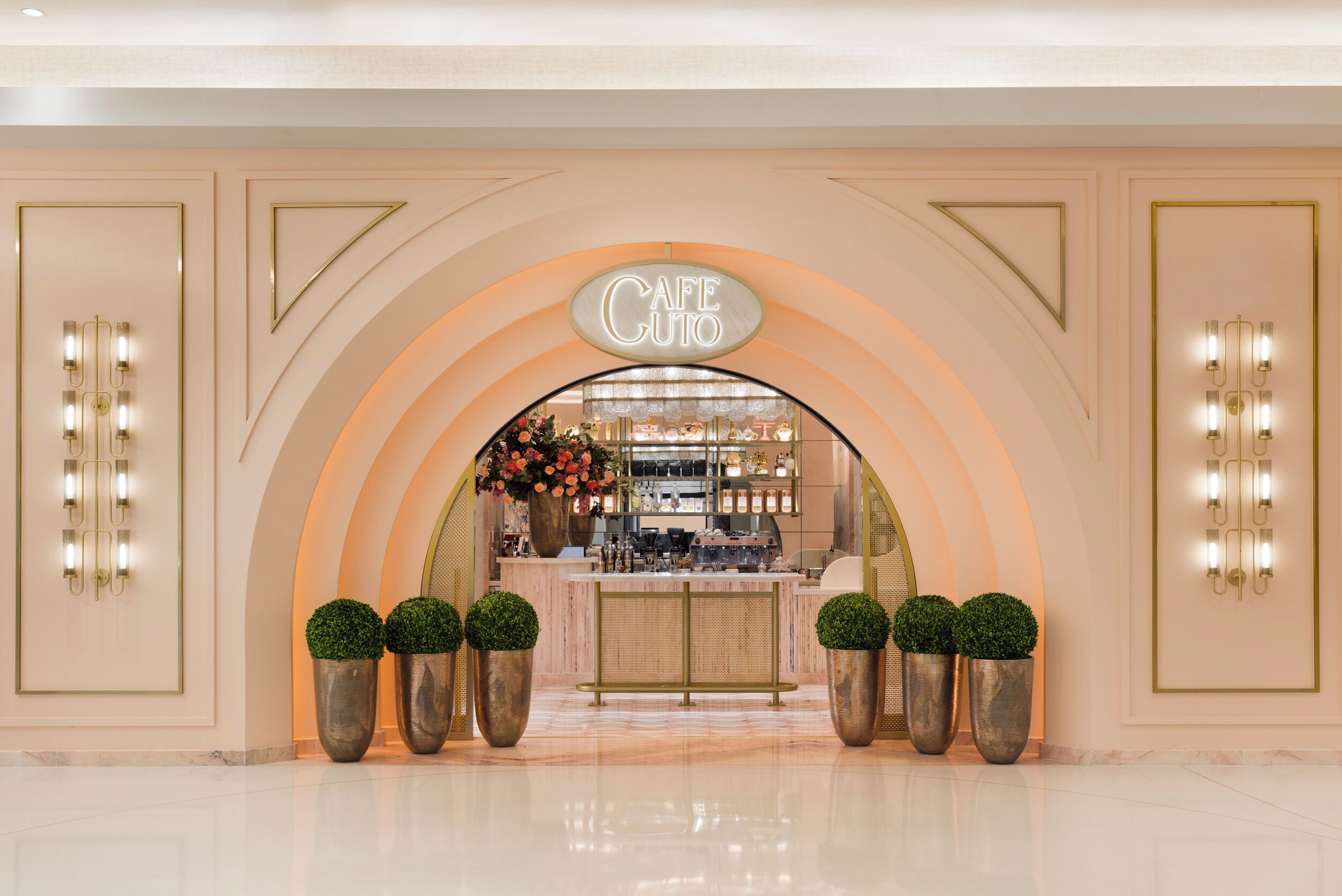 A cafe with a modern design, featuring a large illuminated sign, a counter with a display of items, and decorative lighting.