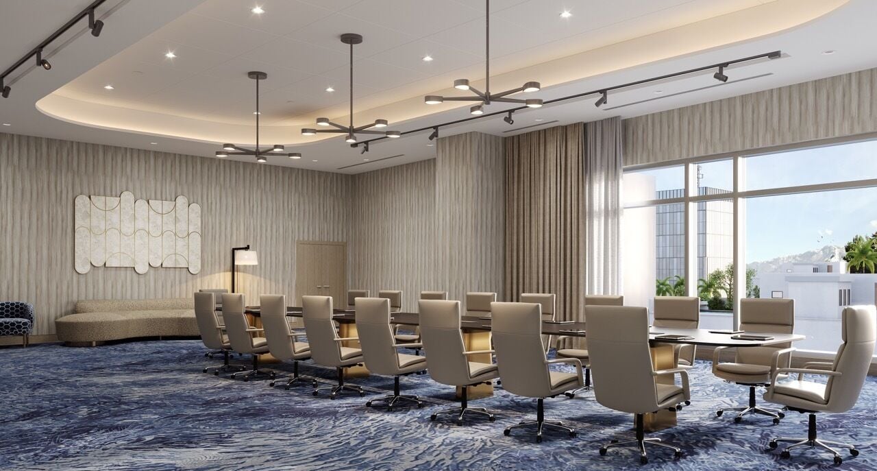 A modern conference room with a round table, beige chairs, and a blue carpet.