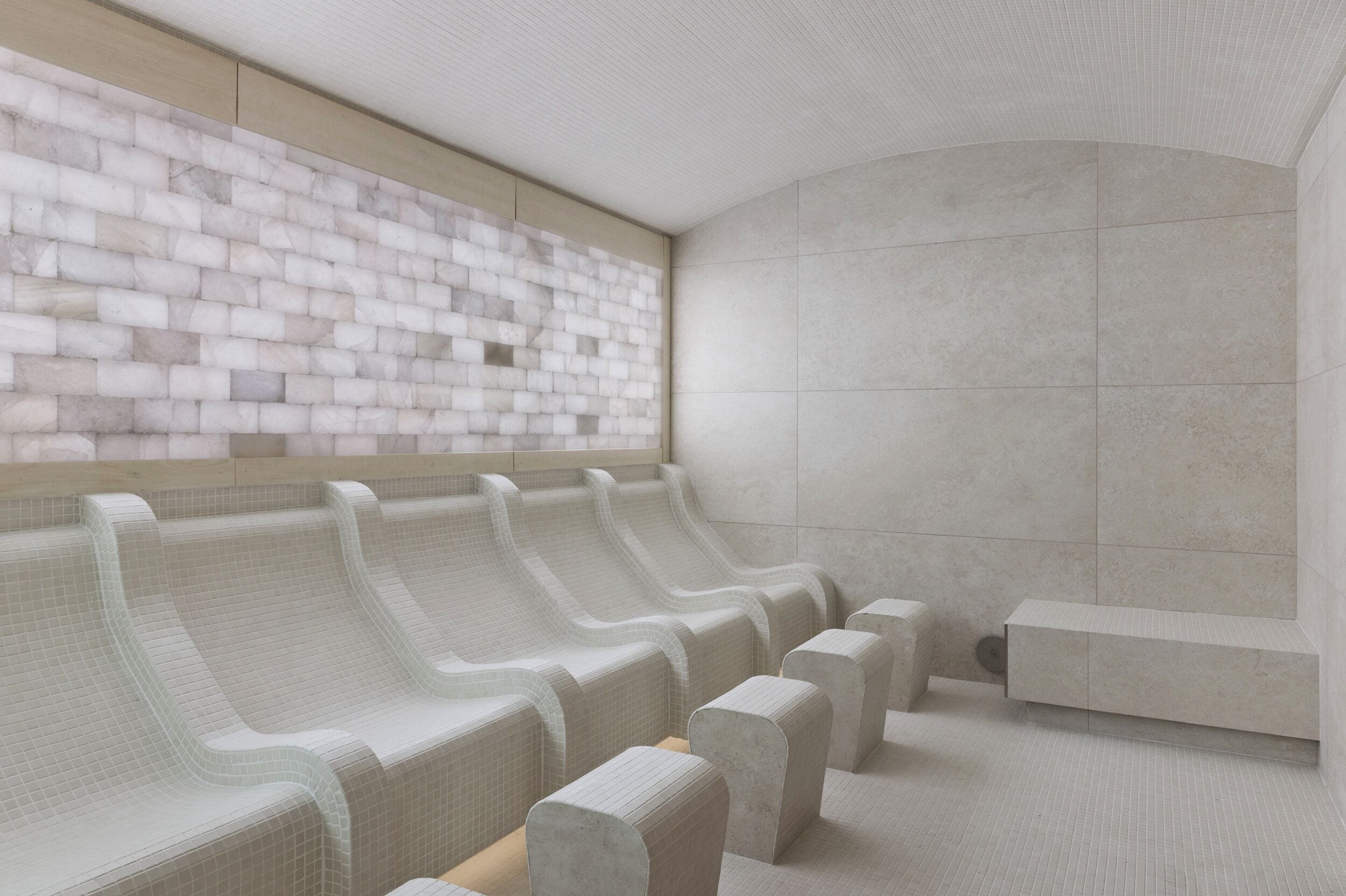 A row of benches with a textured wall behind them.