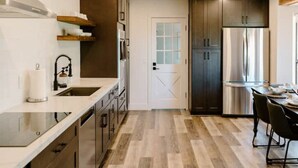 Une cuisine moderne dotée d’appareils électroménagers en acier inoxydable, de meubles en bois et d’un plancher en bois clair.