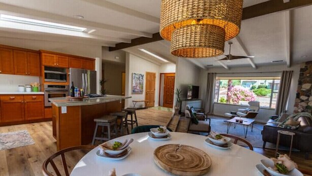 Uma cozinha moderna com armários de madeira, uma ilha central e um espaço de refeições com uma mesa redonda para quatro pessoas.