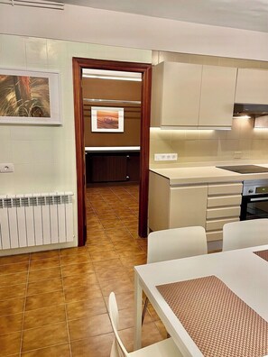 A modern kitchen with a dining area, featuring a built-in oven, a countertop with a sink, and a dining table with chairs.