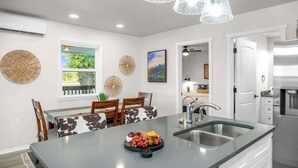 Een moderne keuken met een centraal eiland, een eetgedeelte met uitzicht en een groot raam.