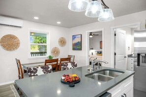 A modern kitchen with a central island, a dining area with a view, and a large window.