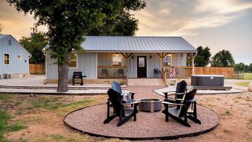 Eine rustikale Holzhütte mit Veranda, Sitzgelegenheit im Freien und einem Feuerkorb.
