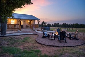 A rustic cabin with a porch, outdoor seating, and a fire pit.