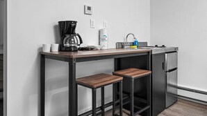 A compact kitchenette with a coffee maker, a sink, and a refrigerator.