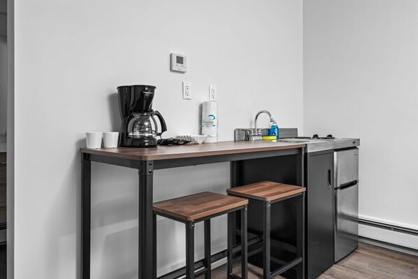 A compact kitchenette with a coffee maker, a sink, and a refrigerator.
