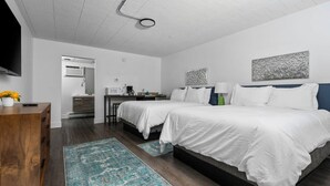 A modern hotel room with a large bed, a desk, a chair, a TV, and a bathroom visible through an open door. - Close to Beaches and Downtown (Traverse City)