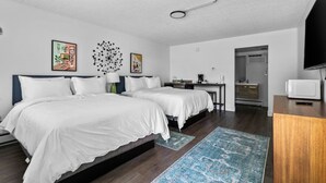 Una habitación de hotel moderna con dos camas, un escritorio, un televisor y una kitchenette.