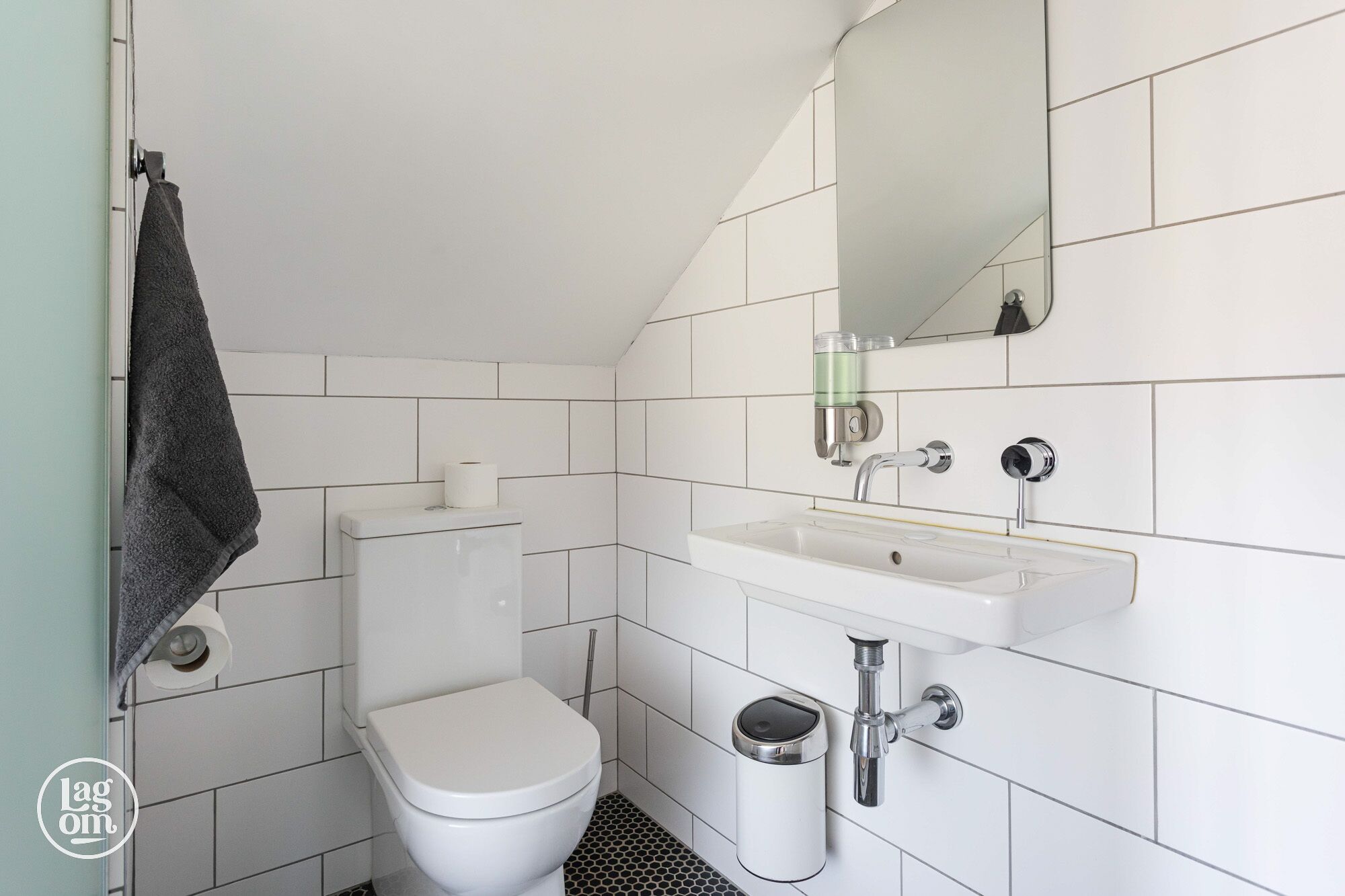 Un baño moderno con inodoro, lavabo y espejo.