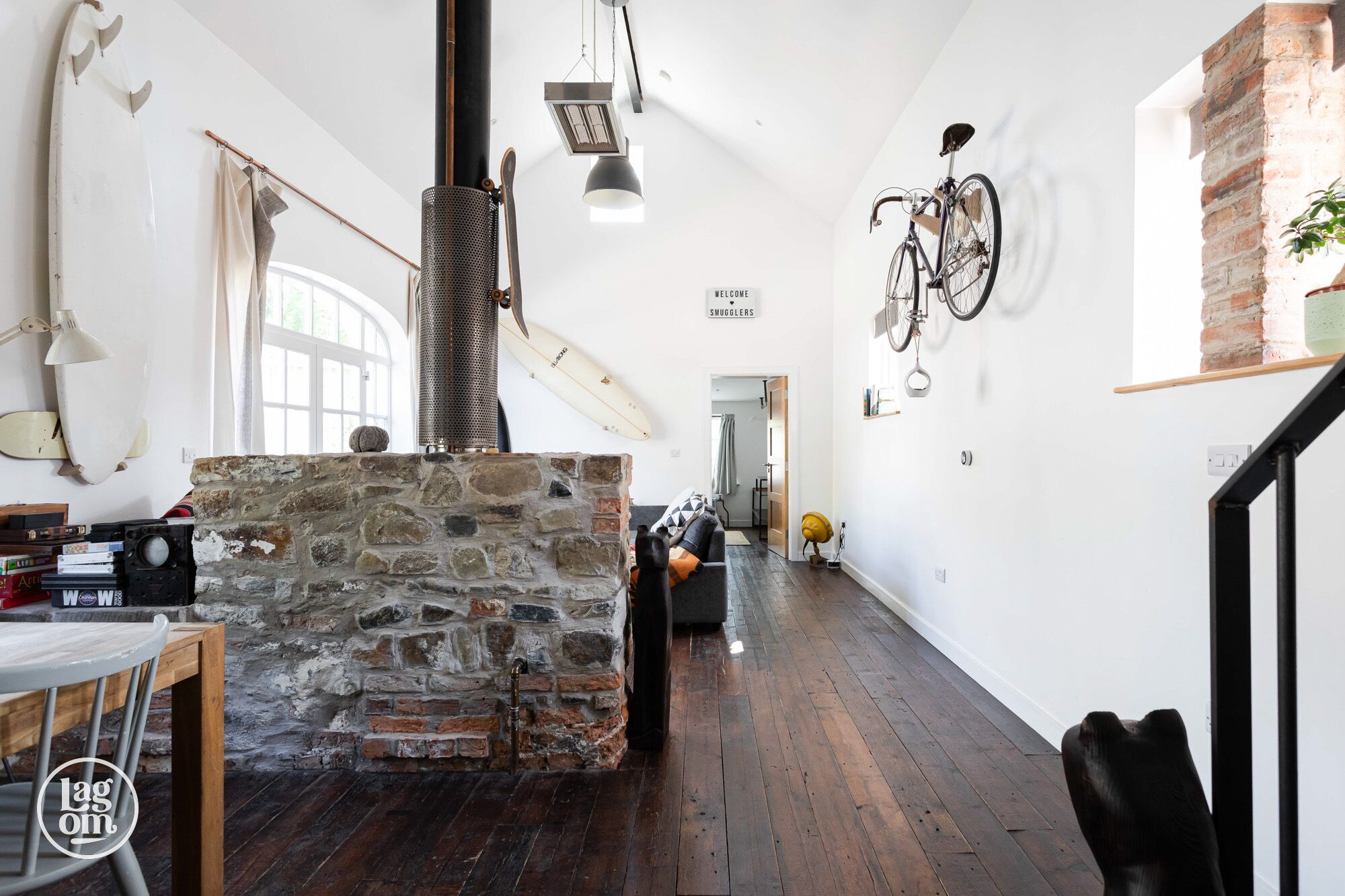 A spacious, well-lit interior with a stone wall, wooden flooring, and a bicycle mounted on the wall.