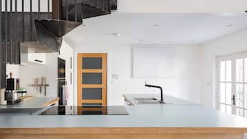 A modern kitchen with a central island, a built-in oven, and a wooden door.