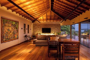 A spacious living area with a stone wall, wooden ceiling, and a large TV.