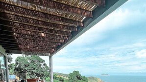 An outdoor dining area with a view of the ocean, featuring a table set with fruits, bread, and a dessert. - Casa Mirador Boutique Hotel (Búzios)