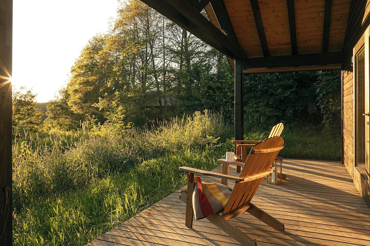 A wooden deck with a covered area, a chair, and a table with a cup.