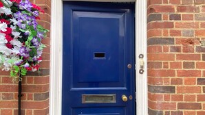 Une porte bleue avec un cadre blanc, une petite fenêtre au-dessus et une enseigne au-dessus de la porte indiquant « The Old Exchange ».