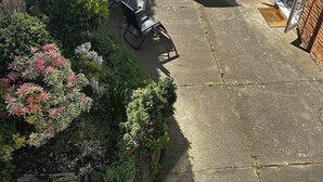 Une cour avec des sièges en plein air, un bâtiment en briques et des plantes en pot.