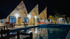 A resort with thatched-roof buildings, a swimming pool, and outdoor seating. - MKEKA SPICE LODGE (Jambiani)