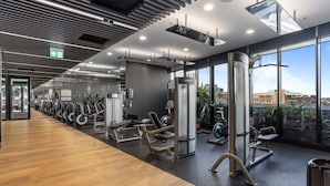 Ein modernes Fitnessstudio mit Trainingsgeräten, großen Fenstern und Blick auf die Stadt.