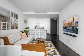 A modern living room with a sofa, coffee table, and a TV mounted on the wall.