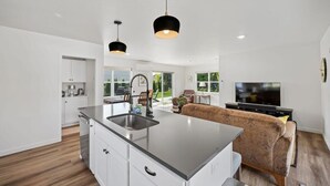 A modern kitchen with a central island, white cabinetry, and black pendant lighting.