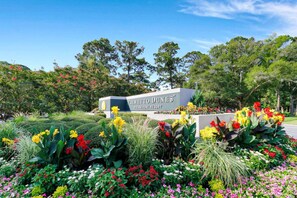 A sign for Palmetto Dunes Oceanfront Resort surrounded by a variety of colorful flowers and greenery.