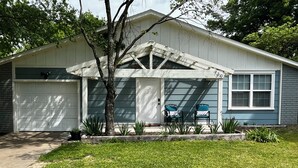 A single-story house with a garage, a covered porch with two chairs, and a small garden area. - 3BR/1BA BROKEN ARROW HOME (Broken Arrow)