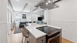 Une cuisine moderne dotée d’un îlot central, de meubles blancs et d’un ventilateur de plafond.