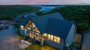 Uma casa moderna com um alpendre grande e vista para um lago ao anoitecer.