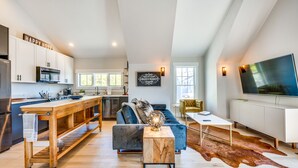 A modern kitchen with white cabinets, a wooden island, and a large flat-screen TV. - 14 Mi to Dtwn Denver: Sleek Westminster Home (Westminster)