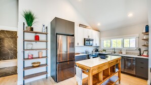 A modern kitchen with a central island, stainless steel appliances, white cabinetry, and a marble backsplash. - 14 Mi to Dtwn Denver: Sleek Westminster Home (Westminster)