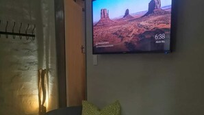 A room with a flat-screen TV mounted on the wall displaying a desert landscape.