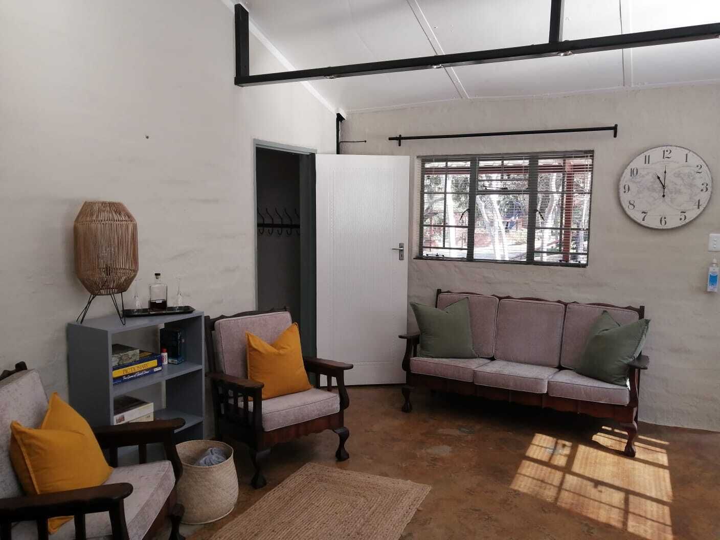 A living room with a sofa, chairs, a bookshelf, and a large wall clock.