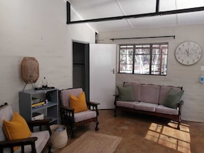 Ein Wohnzimmer mit einer Couch, Sesseln, einem Bücherregal und einer großen Wanduhr.