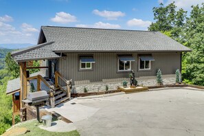A two-story building with a covered porch, a stone wall, and a statue of a bear. - Gorgeous Gatlinburg Cabin: Large Deck & Hot Tub! (Gatlinburg)